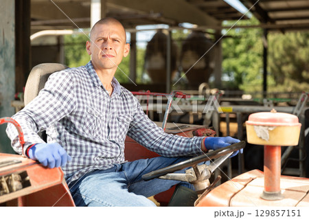 Professional farmer sitting in a tractor at a farm 129857151