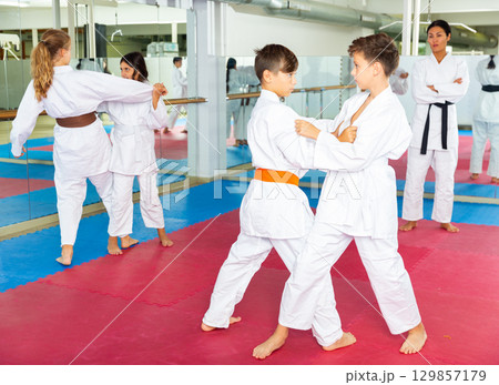 Young girls and boys sparring during karate training Young girls and boys sparring during karate training 129857179