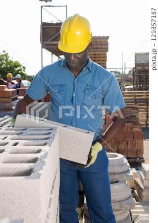 African man checking quality of bricks at construction store 129857187