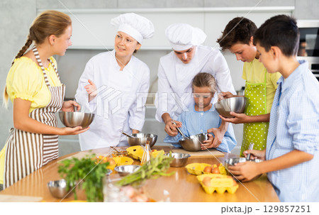Chef apprentices learn how to properly beat eggs with a whisk in cooking class 129857251