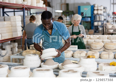 Man ceramist working in pottery workshop 129857388