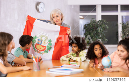 Female teacher showing peruvian flag to kids in geography class 129857565