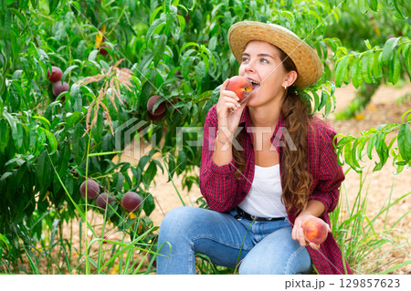 Young lady eating juicy peach 129857623
