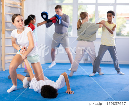 Self-defense - girl twists the arm of an attacking boy during self defense training Self-defense - girl twists the arm of an attacking boy during self defense training 129857637