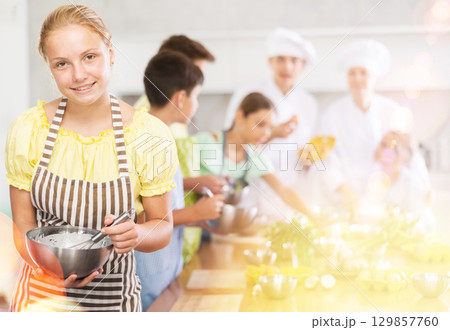 Interested teenage girl participating in culinary class of children group Interested teenage girl participating in culinary class of children group 129857760