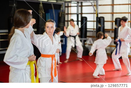 Teenage girls in white kimono at karate lesson Teenage girls in white kimono at karate lesson 129857771