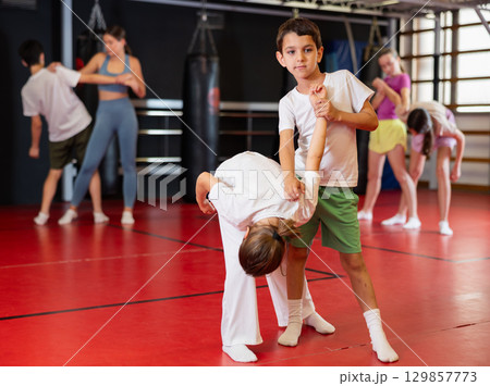 Purposeful engrossed boy and girl train during self-defense fight training session in gym Purposeful engrossed boy and girl train during self-defense fight training session in gym 129857773