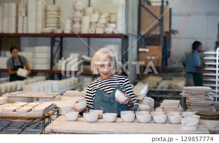 Elderly woman ceramist working in pottery workshop 129857774