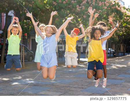 Group of cheerful young girls and boys jumping together 129857775