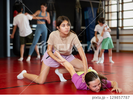 Purposeful engrossed teen girls train during self-defense fight training session in gym 129857787