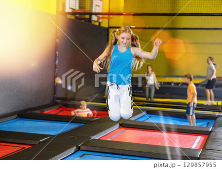 Teen girl jumping on trampoline on indoor inflatable playground Teen girl jumping on trampoline on indoor inflatable playground 129857955