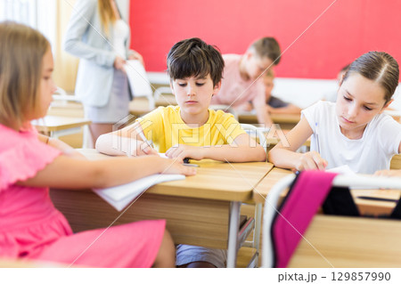 Preteen schoolchilds working in groups at lesson 129857990