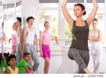 Female dance instructor demonstrating ballet movement to teenage students in studio Female dance instructor demonstrating ballet movement to teenage students in studio 129857993