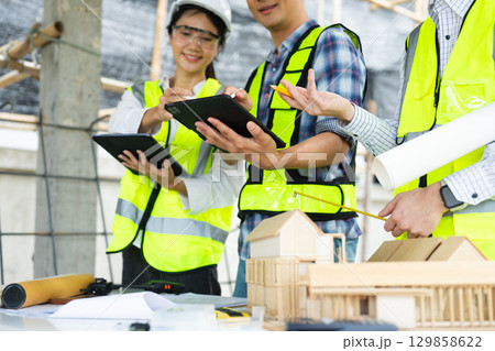 Engineer teams meeting working together wear worker helmets hardhat on construction site in city. Engineer teams meeting working together wear worker helmets hardhat on construction site in city. 129858622