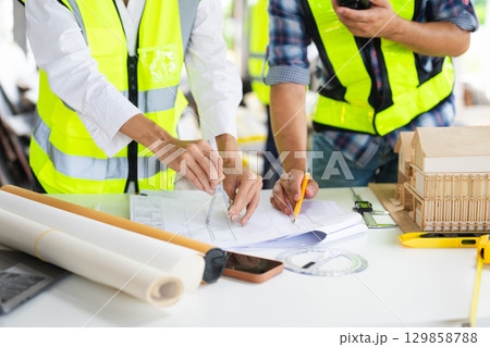 Creative architect projecting on the big drawings with architectural project at construction site at desk Creative architect projecting on the big drawings with architectural project at construction site at desk 129858788