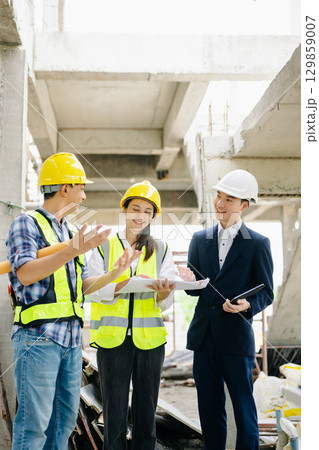 Contractor and architect looking at plan, tablet, laptop and talking about working on big project. Contractor and architect looking at plan, tablet, laptop and talking about working on big project. 129859007