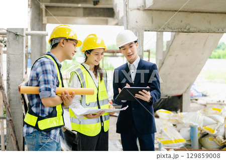 Contractor and architect looking at plan, tablet, laptop and talking about working on big project. Contractor and architect looking at plan, tablet, laptop and talking about working on big project. 129859008