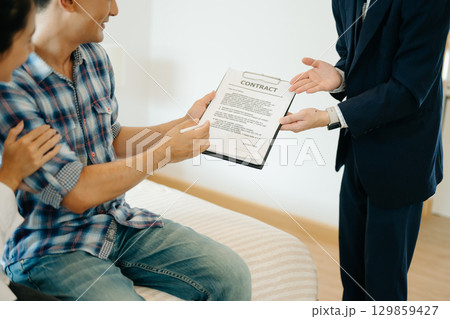 Asian man Real estate broker agent showing a house detail in her file to the young Asian couple lover looking and interest to buy it. Asian man Real estate broker agent showing a house detail in her file to the young Asian couple lover looking and interest to buy it. 129859427