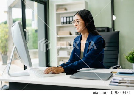 Asian woman sitting at a desk using a laptop computer Navigating Finance and Marketing 129859476