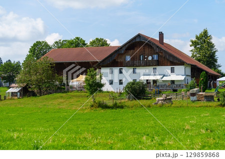 Picturesque Bavarian Farmhouse Amidst Rolling Green Fields Under a Sunny Blue Sky, Bavaria, Germany Picturesque Bavarian Farmhouse Amidst Rolling Green Fields Under a Sunny Blue Sky, Bavaria, Germany 129859868