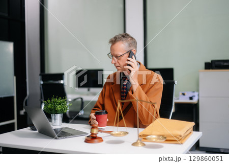 justice and law concept. Male judge in a courtroom the gavel, working with smart phone and laptop 129860051