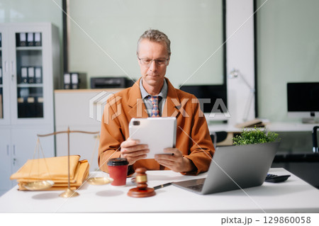 justice and law concept. Male judge in a courtroom the gavel, working with smart phone and laptop 129860058