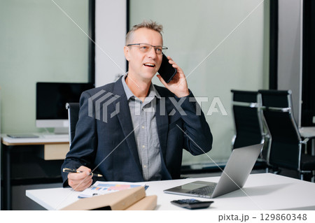 Professional businessman working at office with laptop, tablet, and notes. Perfect for business, finance, accounting Professional businessman working at office with laptop, tablet, and notes. Perfect for business, finance, accounting 129860348