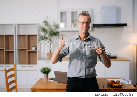 Caucasian man using laptop while sitting at home. man in kitchen and working on laptop 129860358