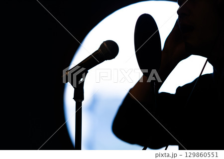 ボイストレーニングをしてレコーディングする若い男性　顔無し 129860551
