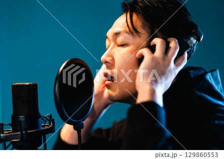 ボイストレーニングをしてレコーディングする若い男性 129860553