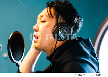 ボイストレーニングをしてレコーディングする若い男性 129860557