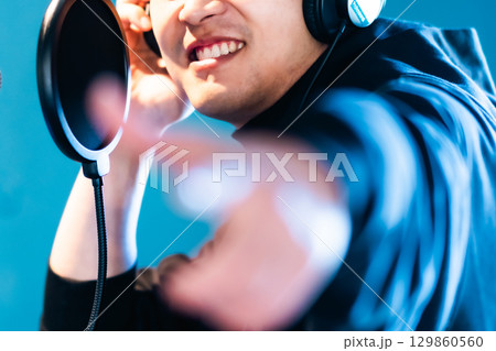 ボイストレーニングをしてレコーディングする若い男性　顔無し 129860560