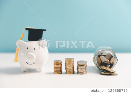 Concept of saving money for education, student loan, scholarship in future. Piggy bank with graduation hat, stack of coins. Earth globe with graduation hat, dollar banknotes on table. Tuition fees Concept of saving money for education, student loan, scholarship in future. Piggy bank with graduation hat, stack of coins. Earth globe with graduation hat, dollar banknotes on table. Tuition fees 129860753