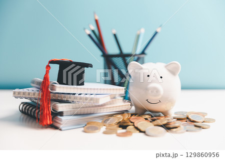 Concept of saving money for education, student loan, scholarship in future. Piggy bank with graduation hat, stack of coins. Earth globe with graduation hat, dollar banknotes on table. Tuition fees 129860956