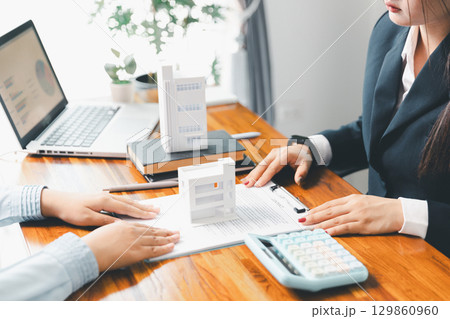 Home loan officer uses calculator with house plan loan real estate or property. important to loan calculator seek real estate, finance insurance advice ensure smart financial decisions for business. 129860960