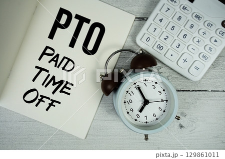 PTO Paid Time Off text on paper notebook page with alarm clock and calculator on wooden background 129861011