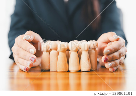 Hands protecting family wooden model for insurance and assurance life concept. Businessman hand gesture protecting wooden domino falling to family dolls for insurance and assurance. Hands protecting family wooden model for insurance and assurance life concept. Businessman hand gesture protecting wooden domino falling to family dolls for insurance and assurance. 129861191