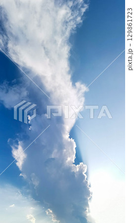 Majestic cloud formation against bright blue sky with sunlight illuminating the scene Vertical shot 129861723