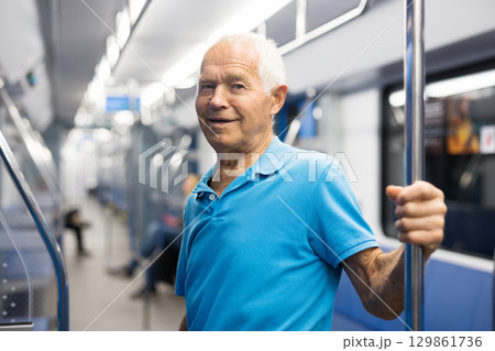 Old man standing in subway car 129861736