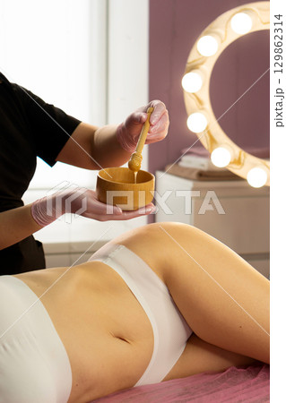 Spa therapist stirring honey mixture before applying to skin. Spa therapist stirring honey mixture before applying to skin. 129862314