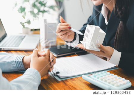 Home loan officer uses calculator with house plan loan real estate or property. important to loan calculator seek real estate, finance insurance advice ensure smart financial decisions for business. 129863458