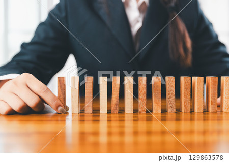 Business risk control concept, Businesswoman protect wooden block fall to planning and strategy in risk to business alternative and prevent. investment insurance business. 129863578