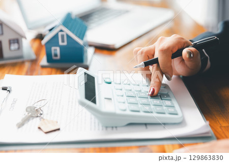 Home loan officer uses calculator with house plan loan real estate or property. important to loan calculator seek real estate, finance insurance advice ensure smart financial decisions for business. Home loan officer uses calculator with house plan loan real estate or property. important to loan calculator seek real estate, finance insurance advice ensure smart financial decisions for business. 129863830