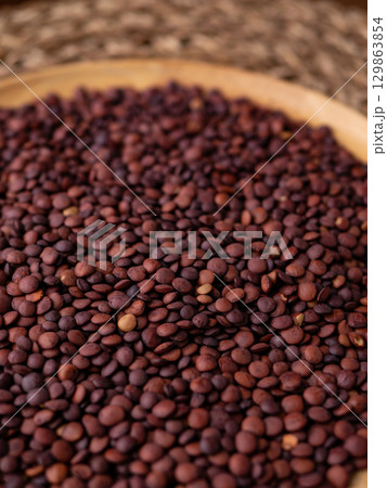 Organic uncooked seeds dark red brown lentils. 129863854