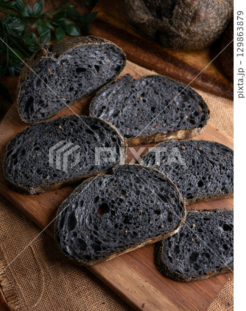 Fresh baked black charcoal sourdough ciabatta bread sliced on wooden board. Fresh baked black charcoal sourdough ciabatta bread sliced on wooden board. 129863879