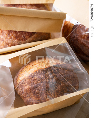 Sourdough Bread Loaf in Transparent Plastic Bag on White Background Ready for Sale or Delivery 129864074