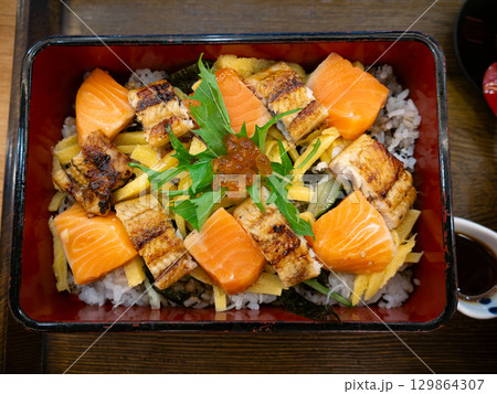 Japanese Bento Box with Unagi Don and Salmon Sashimi. Grilled Eel and Fresh Salmon on rice set. 129864307