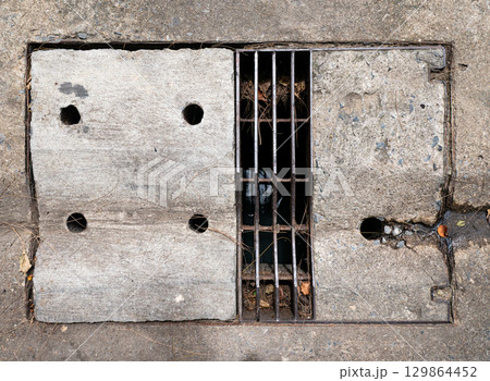 Old Rectangular Urban Drain Cover Made of Metal Grate and Concrete. 129864452