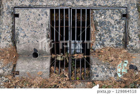 Old Rectangular Urban Drain Cover Made of Metal Grate and Concrete. 129864518