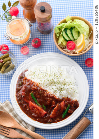 ほかほかと香り立つトマトカレーと白ごはんの盛り付け　サラダ付き家庭料理の食卓イメージ 129865486